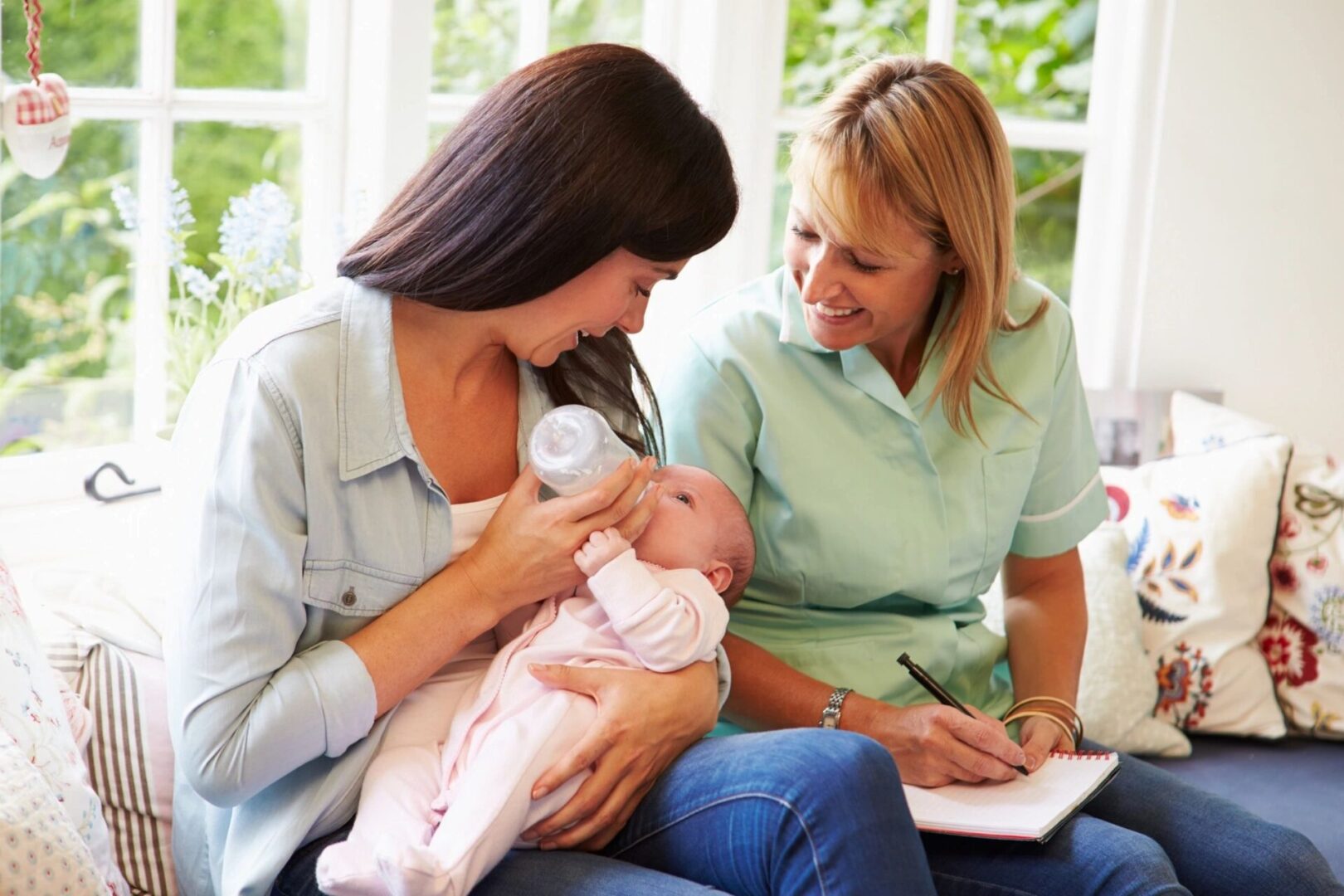 Two women are holding a baby and smiling.